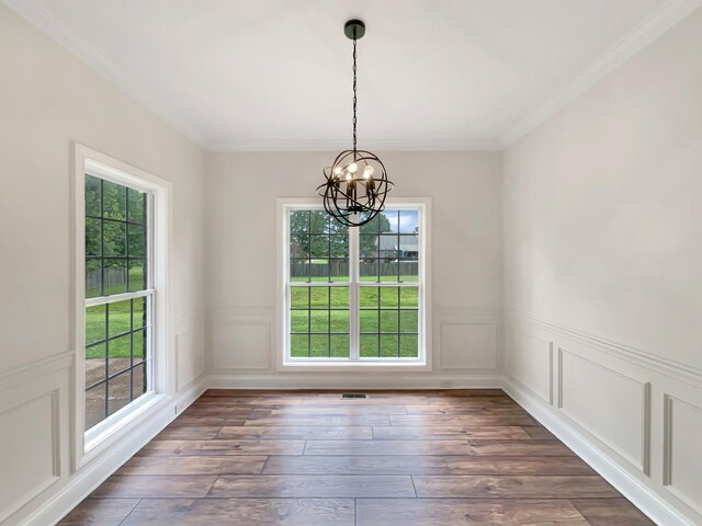 unfurnished dining area featuring a notable chandelier, crown molding, and dark hardwood / wood-style flooring