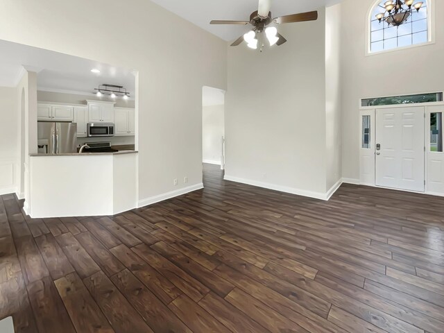 entryway with ceiling fan with notable chandelier, a high ceiling, dark hardwood / wood-style floors, and ornamental molding