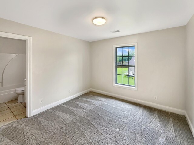 unfurnished bedroom featuring tile patterned flooring and ensuite bath