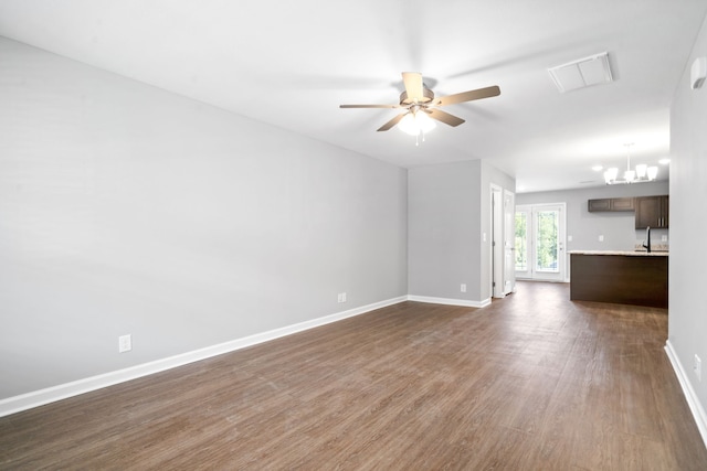 unfurnished living room with visible vents, baseboards, dark wood-type flooring, and ceiling fan with notable chandelier