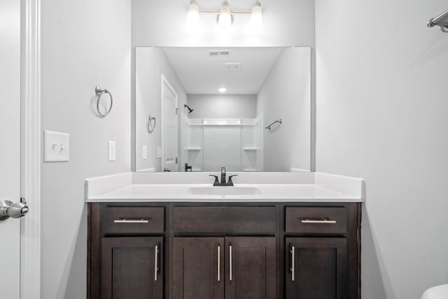 full bathroom with vanity, a shower, and visible vents