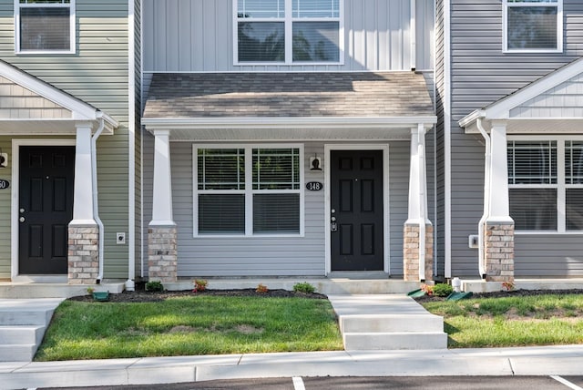 view of exterior entry featuring board and batten siding, stone siding, and a shingled roof