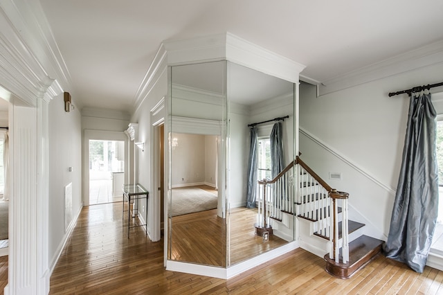 stairs with ornate columns, wood-type flooring, and crown molding