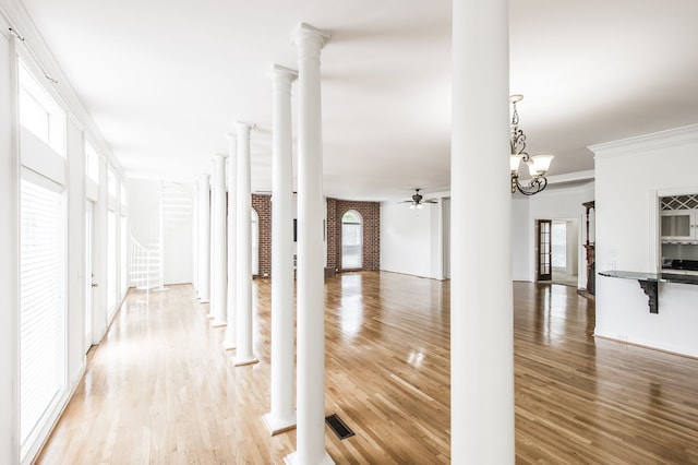 hallway with decorative columns, ornamental molding, and hardwood / wood-style floors