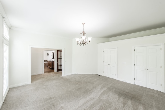 empty room featuring crown molding, light carpet, and a notable chandelier