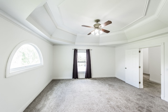 spare room with ceiling fan, ornamental molding, a raised ceiling, and light carpet