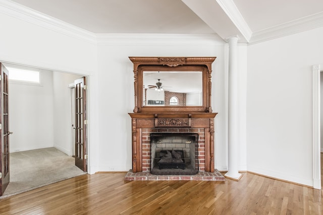 unfurnished living room with crown molding, a brick fireplace, hardwood / wood-style flooring, and ornate columns