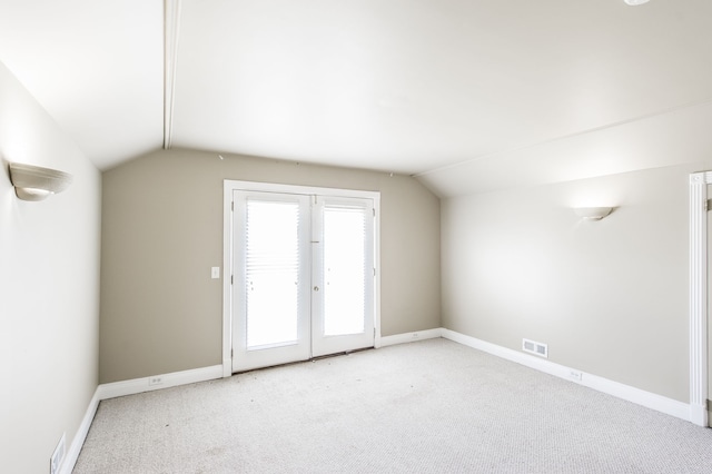 bonus room with vaulted ceiling, light colored carpet, and french doors