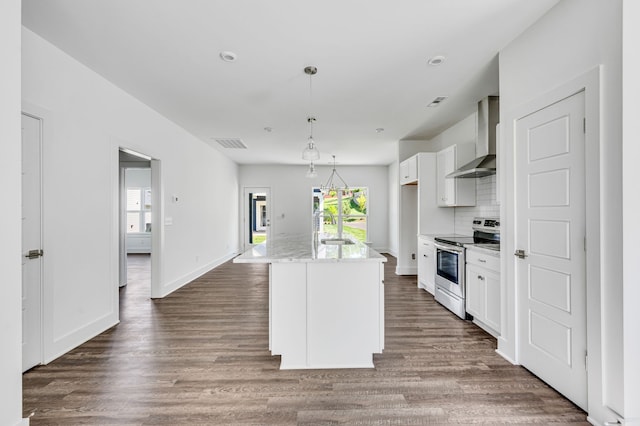 kitchen with wall chimney exhaust hood, electric stove, backsplash, wood-type flooring, and a center island with sink