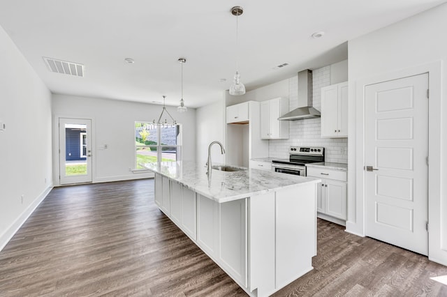 kitchen featuring dark hardwood / wood-style flooring, an island with sink, stainless steel electric range oven, and wall chimney exhaust hood