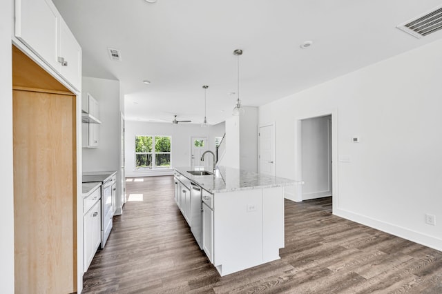 kitchen with sink, white cabinetry, dark hardwood / wood-style flooring, stainless steel appliances, and a kitchen island with sink