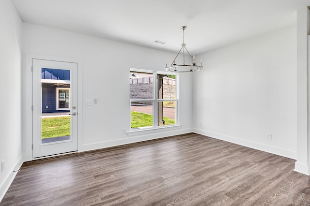 unfurnished room featuring an inviting chandelier and dark hardwood / wood-style flooring