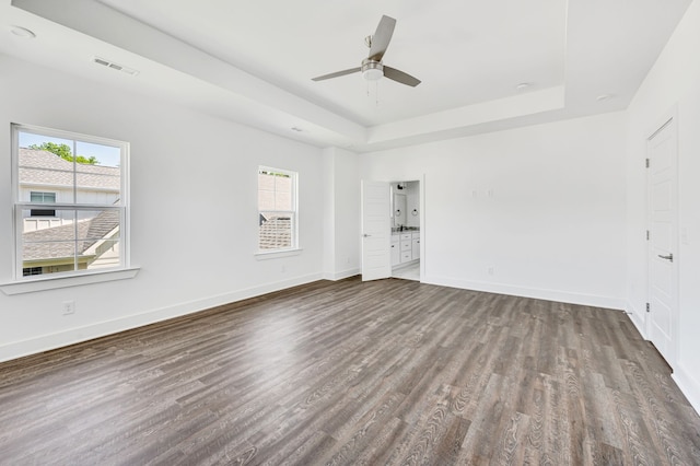 spare room featuring a wealth of natural light, ceiling fan, dark hardwood / wood-style floors, and a raised ceiling