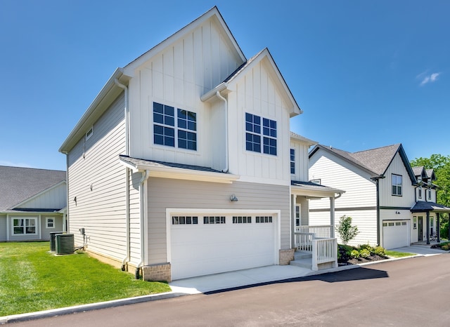 view of front facade with a front yard, a garage, and central AC unit