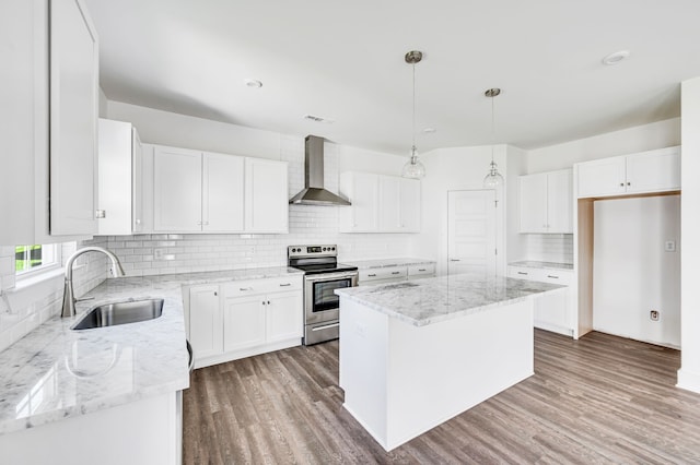 kitchen featuring a center island, wall chimney range hood, hardwood / wood-style flooring, tasteful backsplash, and electric stove