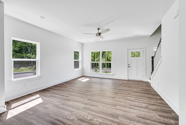 unfurnished living room with dark hardwood / wood-style flooring and ceiling fan