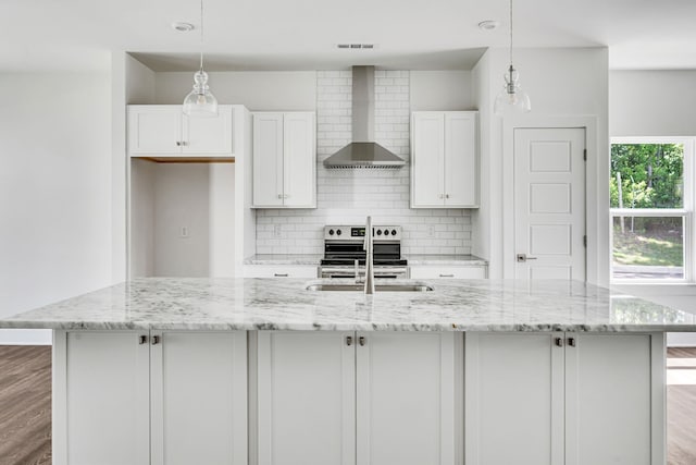 kitchen with a kitchen island with sink, wall chimney range hood, tasteful backsplash, wood-type flooring, and pendant lighting