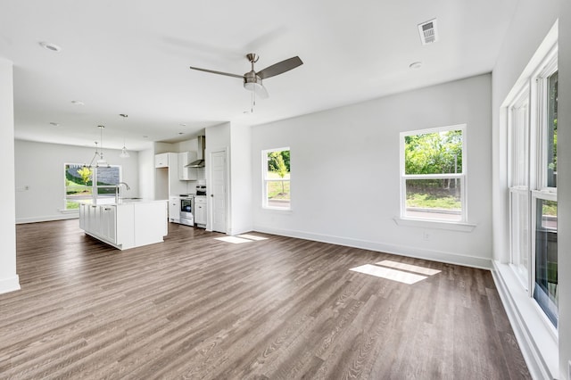 unfurnished living room featuring wood-type flooring, ceiling fan, and sink