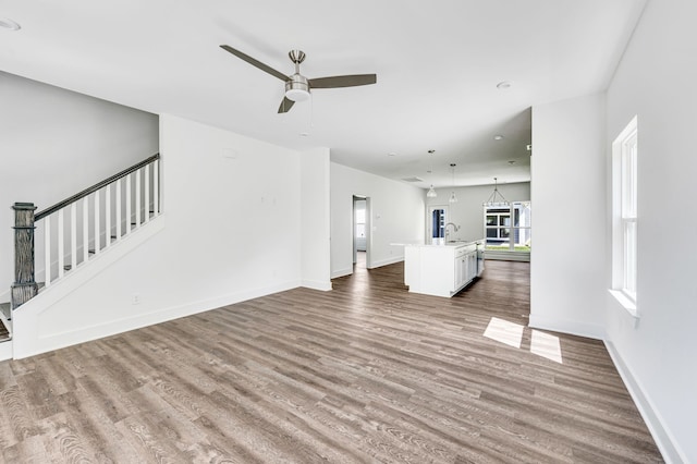 unfurnished living room with wood-type flooring, sink, and ceiling fan