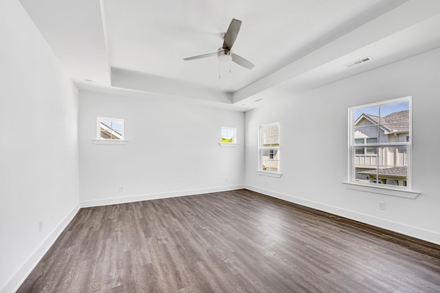 empty room featuring ceiling fan, a raised ceiling, and dark wood-type flooring