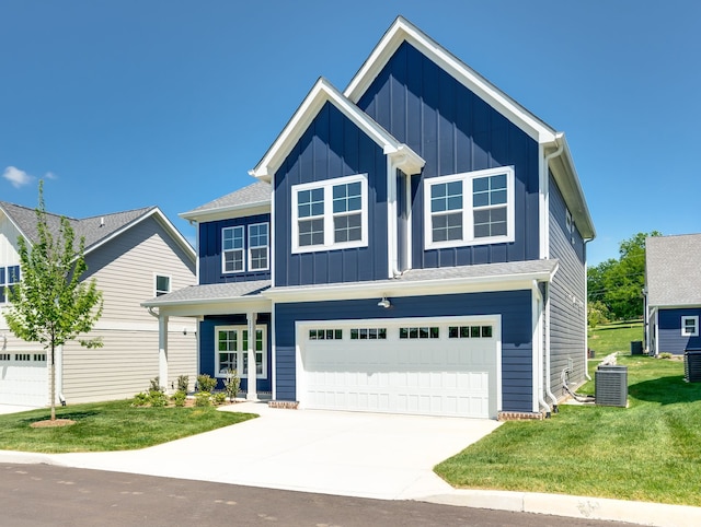 view of front of home with central air condition unit, a garage, and a front yard