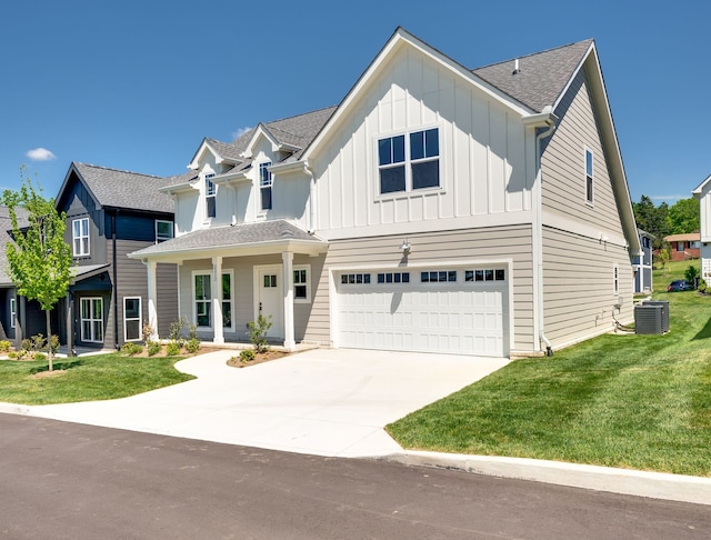 view of front of home featuring a front lawn, a garage, and central air condition unit