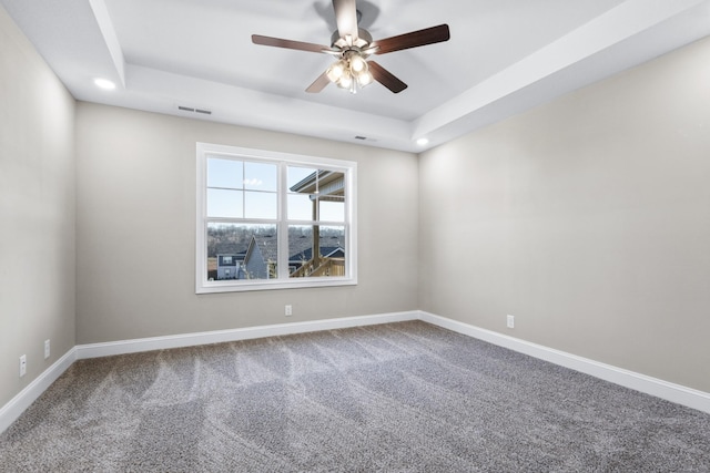 spare room featuring a raised ceiling, ceiling fan, and carpet flooring