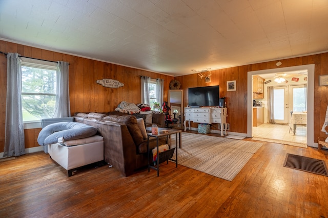 living room with french doors, wood-type flooring, and wood walls