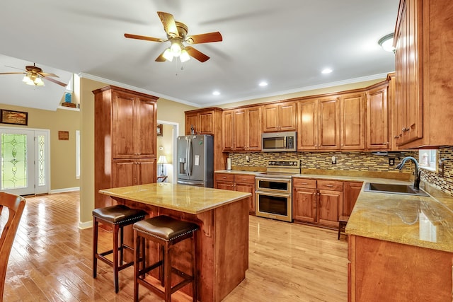 kitchen with light hardwood / wood-style flooring, appliances with stainless steel finishes, a kitchen bar, sink, and tasteful backsplash