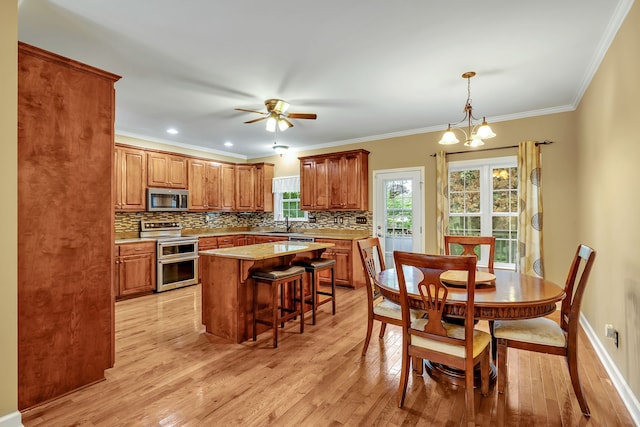 kitchen featuring light hardwood / wood-style flooring, stainless steel appliances, ceiling fan with notable chandelier, tasteful backsplash, and a center island