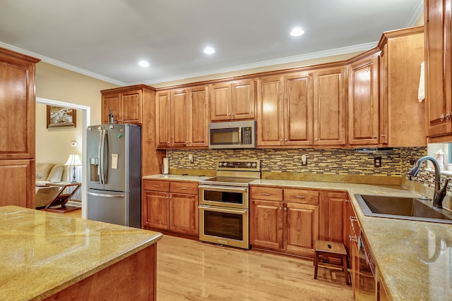 kitchen with appliances with stainless steel finishes, sink, light hardwood / wood-style floors, tasteful backsplash, and crown molding