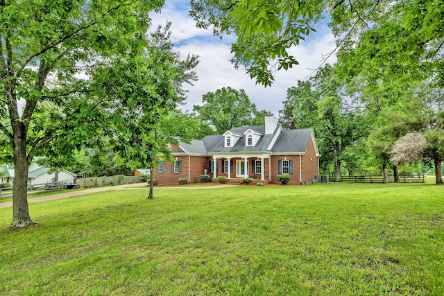 new england style home with central AC and a front yard