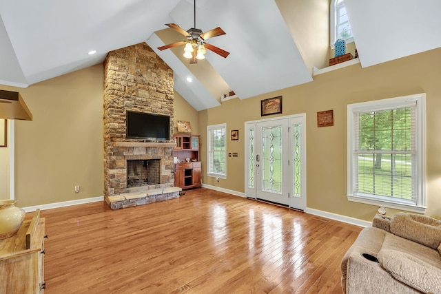 living room with high vaulted ceiling, ceiling fan, light wood-type flooring, and a fireplace