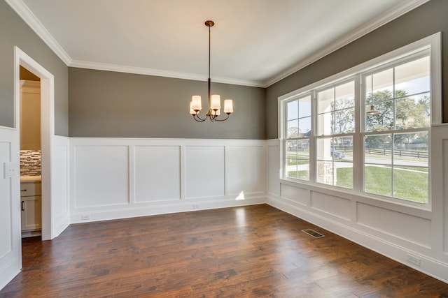 empty room featuring a chandelier, a healthy amount of sunlight, dark hardwood / wood-style floors, and ornamental molding