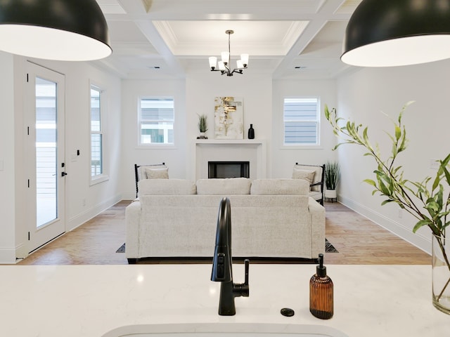 living room with wood-type flooring, sink, a notable chandelier, and coffered ceiling