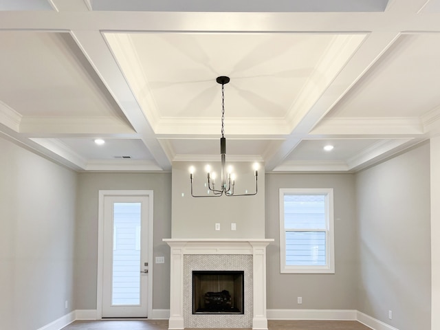 unfurnished living room with ornamental molding, coffered ceiling, a tiled fireplace, and beam ceiling