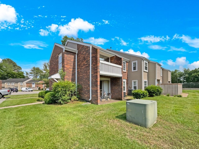 back of property with a yard and a balcony