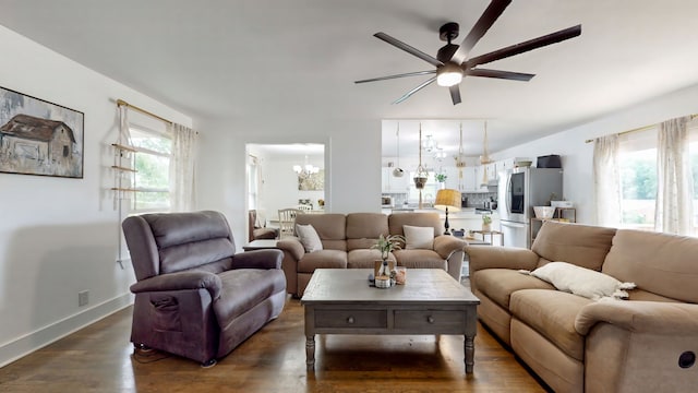 living room with ceiling fan with notable chandelier and dark wood-type flooring