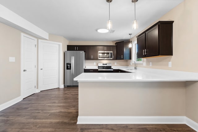 kitchen with dark brown cabinetry, stainless steel appliances, dark hardwood / wood-style floors, kitchen peninsula, and pendant lighting