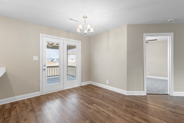 spare room with dark hardwood / wood-style floors and a chandelier