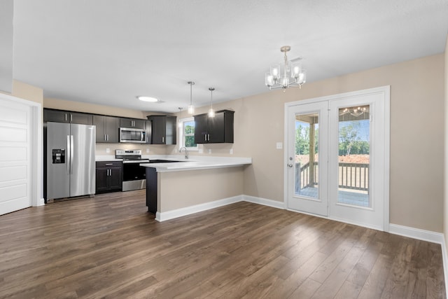 kitchen featuring plenty of natural light, kitchen peninsula, stainless steel appliances, and hanging light fixtures