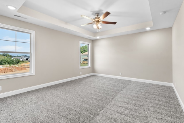 empty room with carpet, a raised ceiling, and ceiling fan