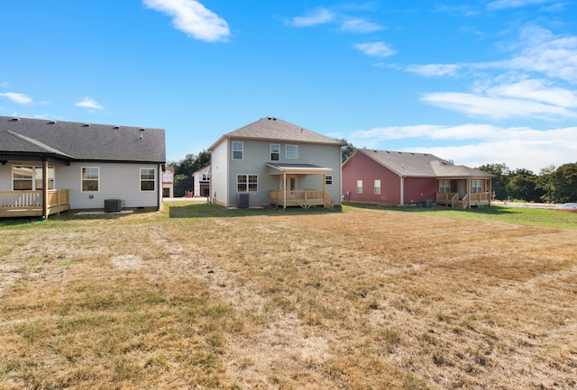 rear view of property featuring a yard, central AC unit, and a wooden deck