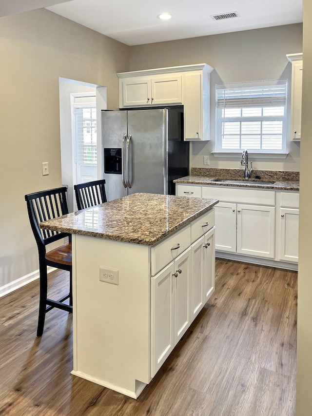 kitchen with wood-type flooring, sink, a center island, and stainless steel fridge with ice dispenser