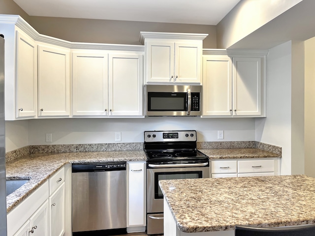 kitchen featuring light stone counters, stainless steel appliances, and white cabinets