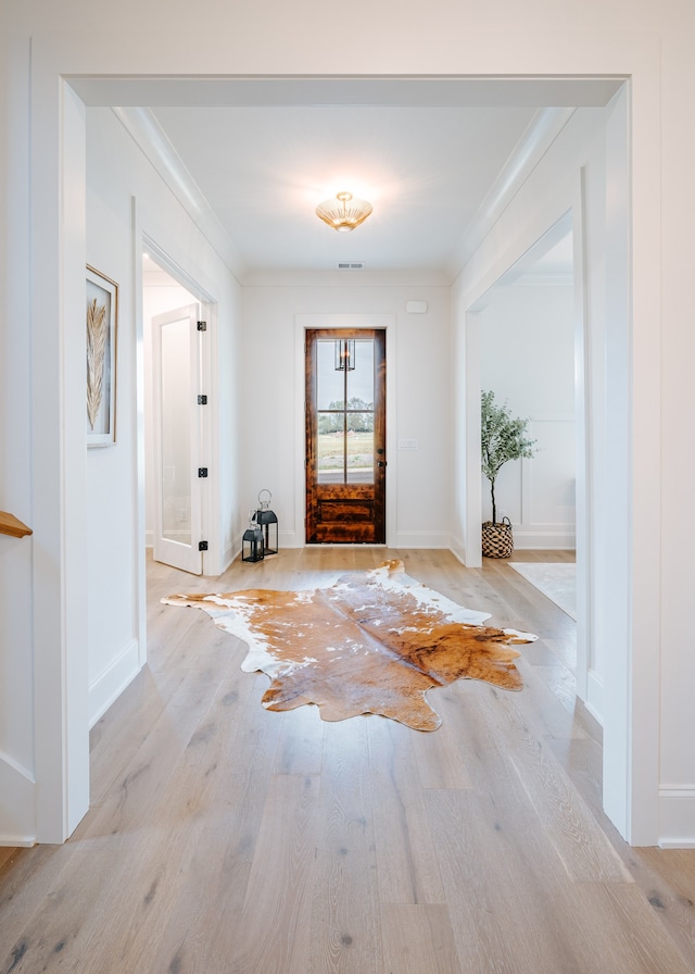 foyer with ornamental molding and light wood-type flooring