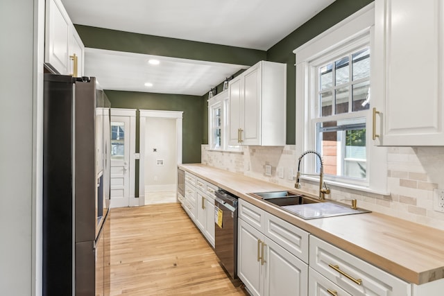 kitchen featuring white cabinets, black dishwasher, stainless steel refrigerator, light hardwood / wood-style flooring, and sink