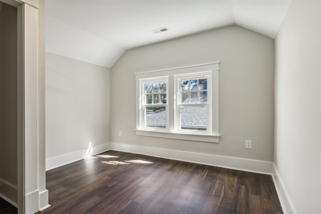 empty room featuring vaulted ceiling and dark hardwood / wood-style floors