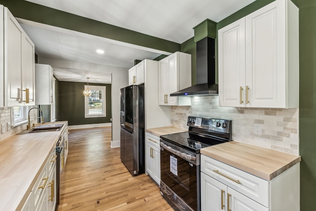 kitchen featuring wall chimney range hood, white cabinetry, wooden counters, and black appliances