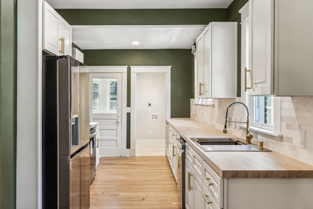 kitchen with appliances with stainless steel finishes, white cabinets, a healthy amount of sunlight, and light hardwood / wood-style floors